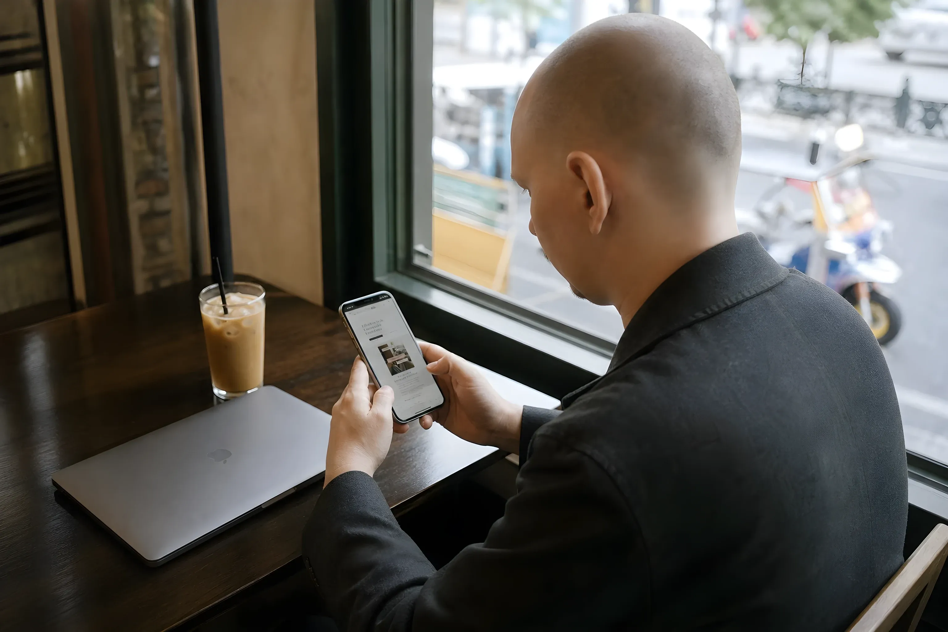 Simon checking the All That’s Stylist Service site on his phone at a café in Bangkok
