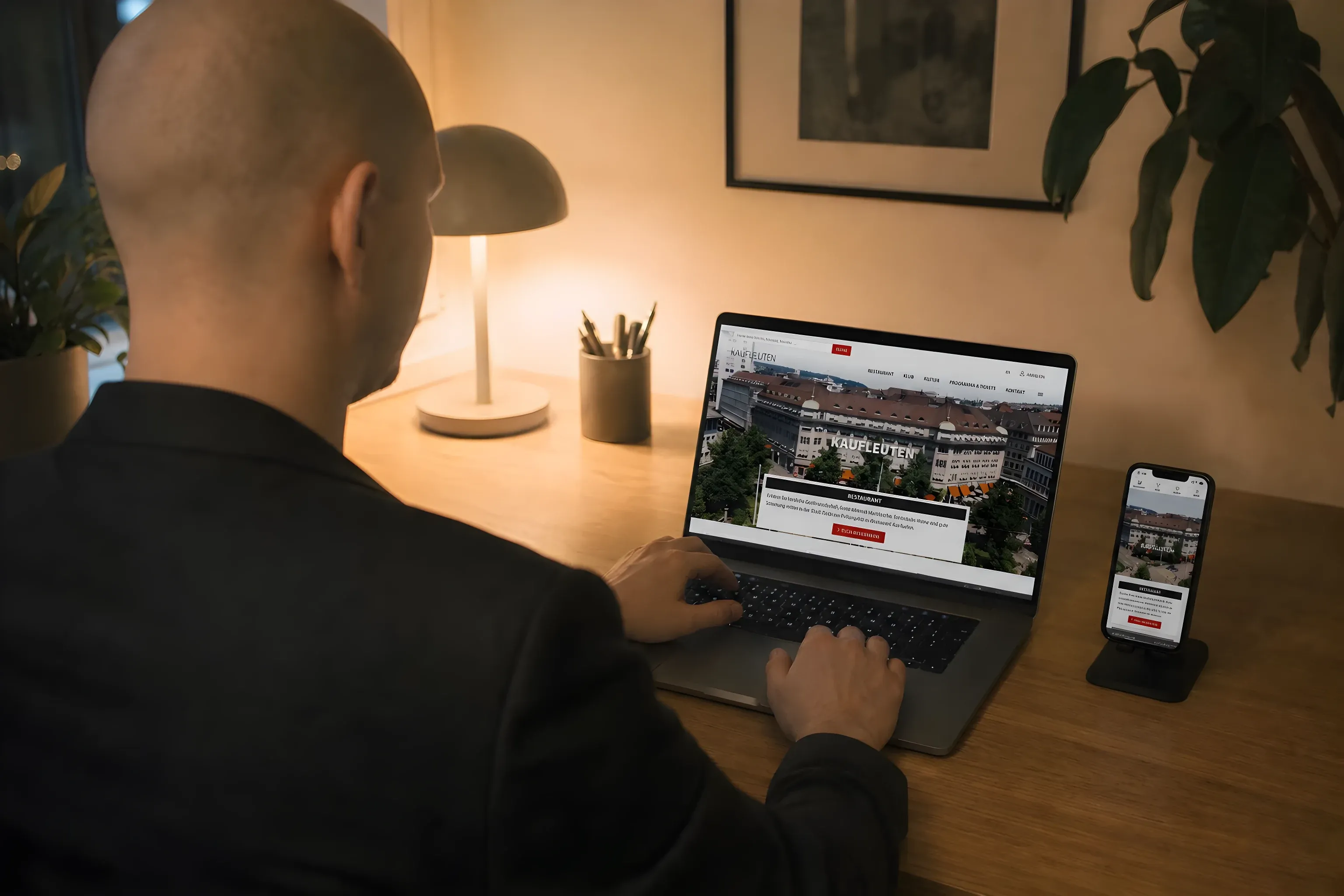 Simon at his desk in the evening with the Kaufleuten site on his laptop and phone
