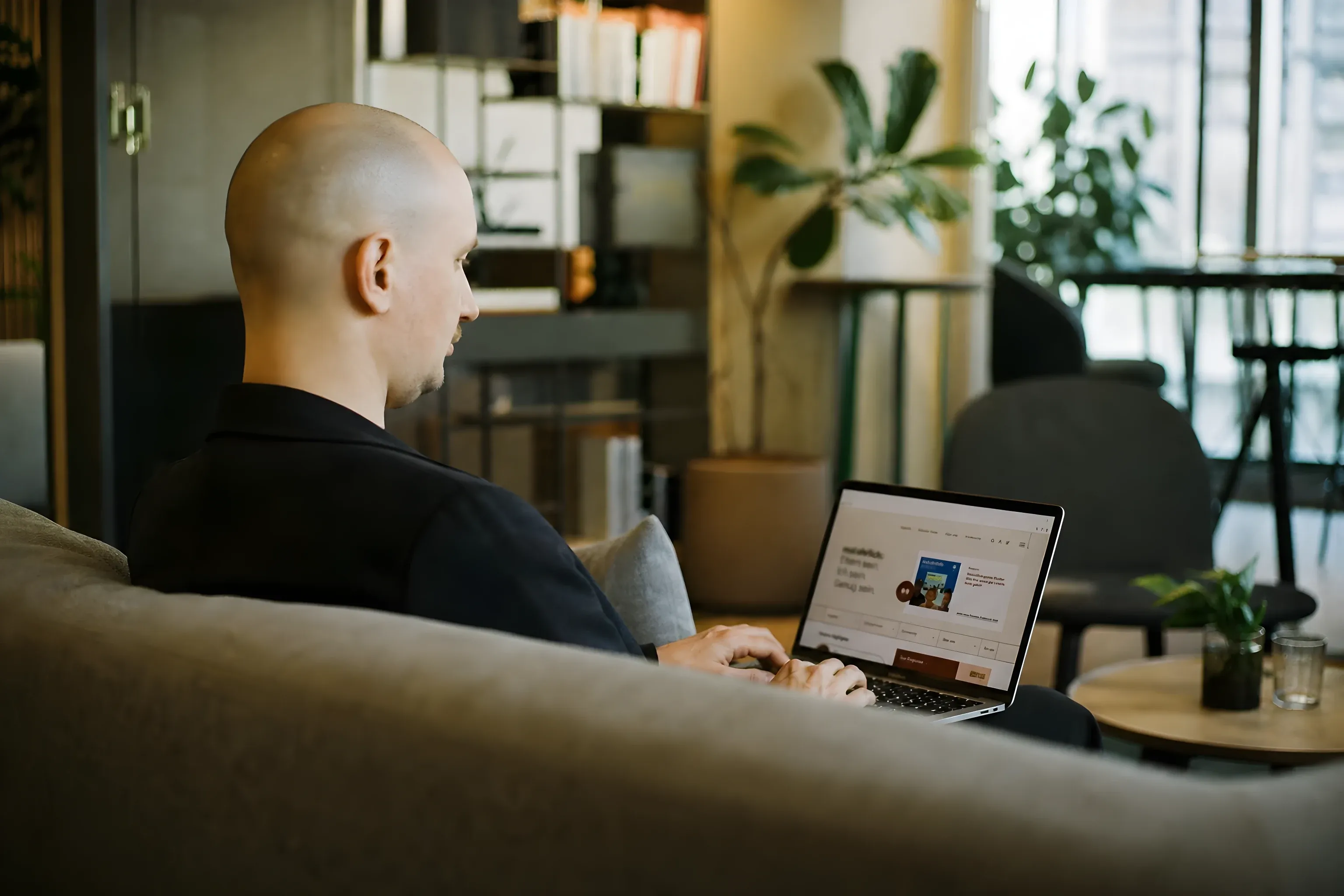 Simon on a coworking sofa with the mal ehrlich site on his MacBook